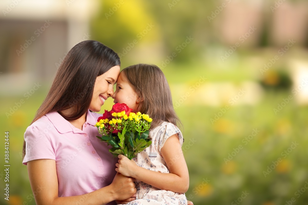 Fototapeta premium Mother and daughter with bouquet of flowers on blurred background.