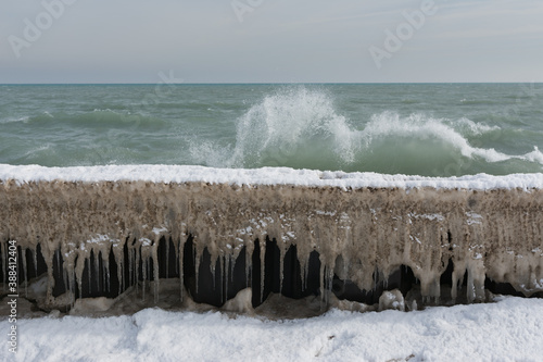 Lake Michigan waves breaking against barricade covered in snow, ice, and icicles 