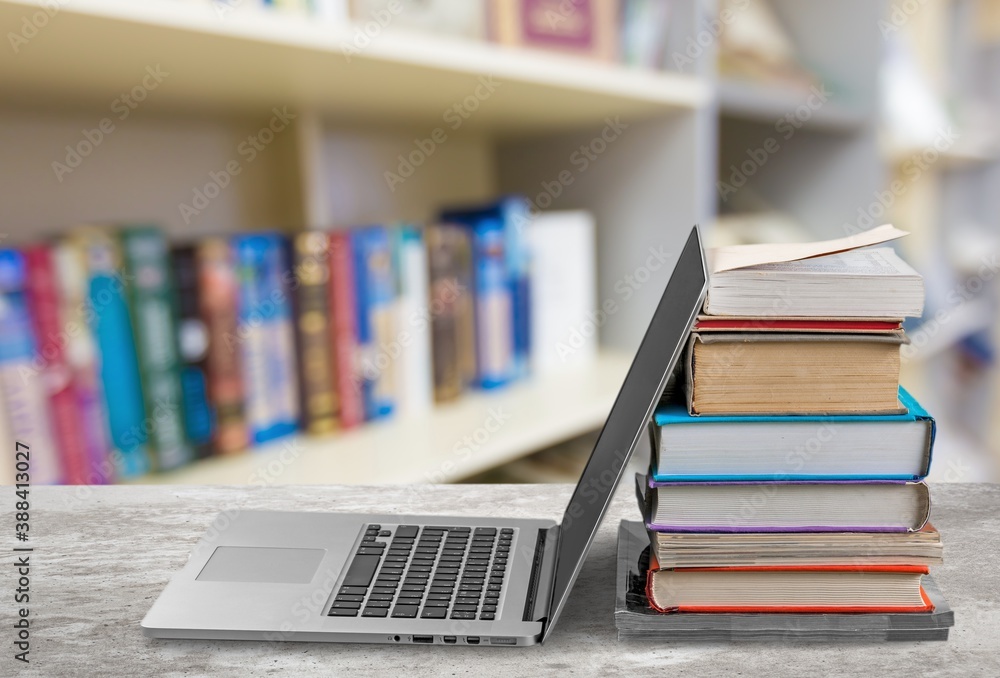 Stack of books with modern laptop on table Stack of books with modern laptop on table