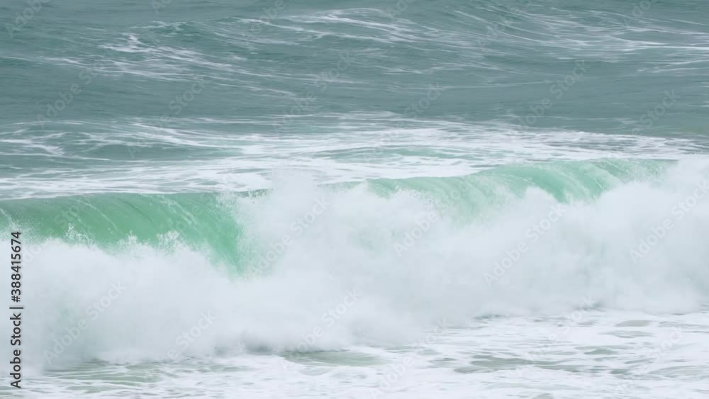 Waves rushing towards the beach, white foam floating on the sea Waves rushing towards the beach, white foam floating on the sea