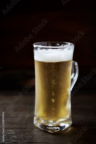 Glass of beer on dark wooden background.