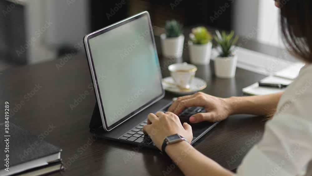 Side view of female hands working with digital tablet on office desk Side view of female hands working with digital tablet on office desk