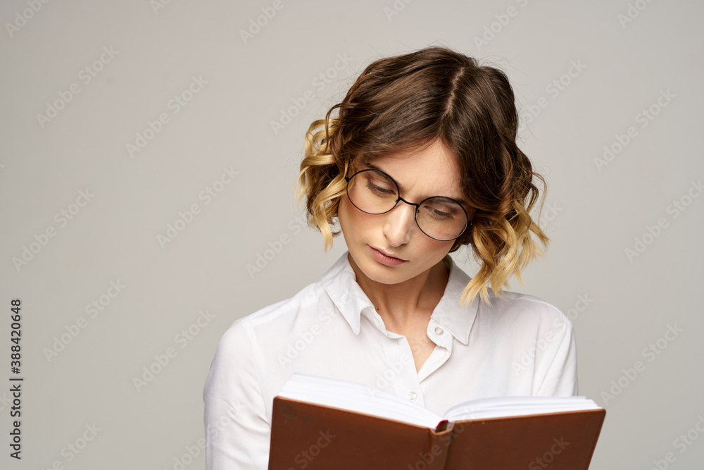 Business woman with notepad and glasses on a light background hairstyle success emotions Business woman with notepad and glasses on a light background hairstyle success emotions
