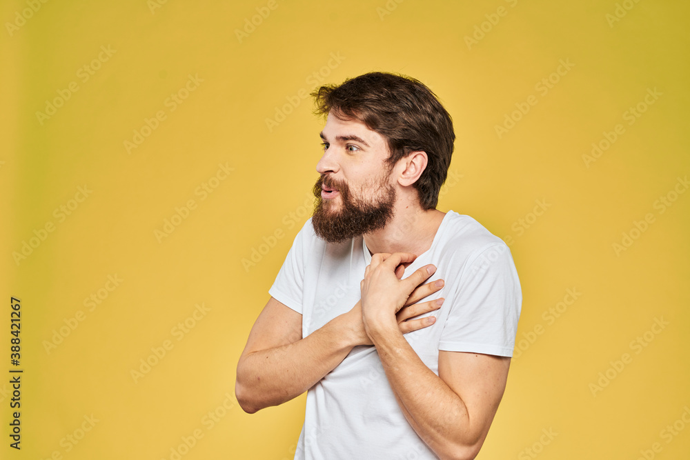 Man gesturing with hands emotions lifestyle white t-shirt yellow isolated background Man gesturing with hands emotions lifestyle white t-shirt yellow isolated background