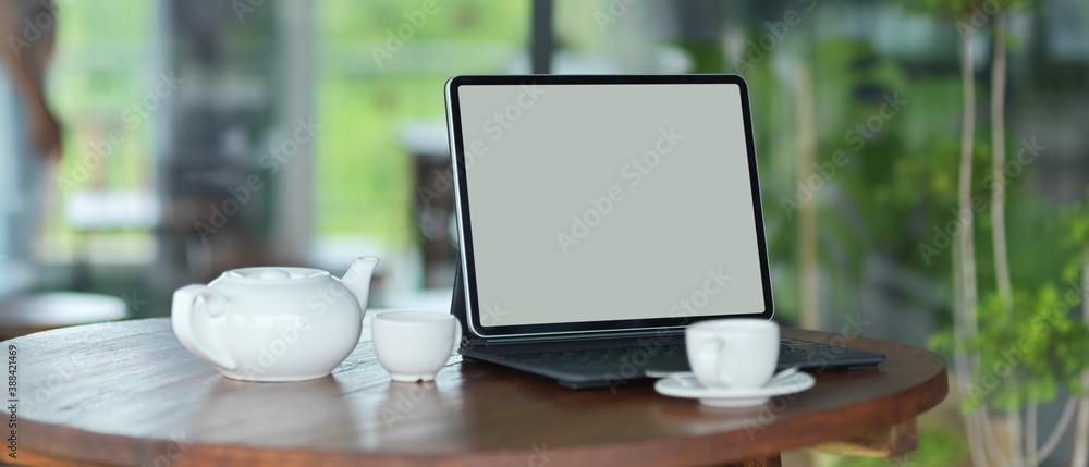 Workspace with mock up blank screen tablet with keyboard with pottery teapot set Workspace with mock up blank screen tablet with keyboard with pottery teapot set