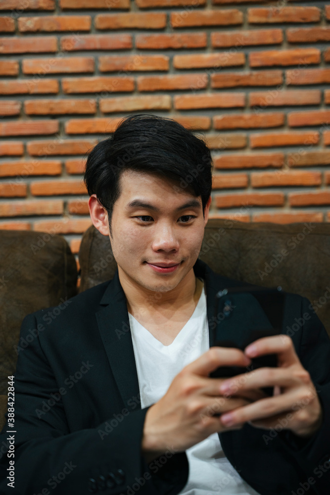 Asian young businessman using smartphone on sofa. Asian young businessman using smartphone on sofa.