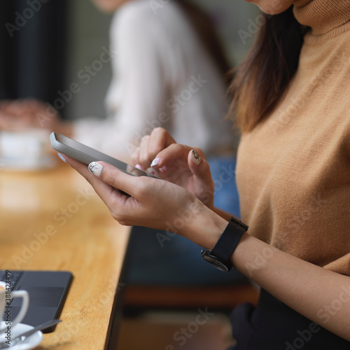 Girl hands using her smartphone in comfortable workspace