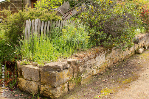 Old sandstone block garden wall and timber picket fence