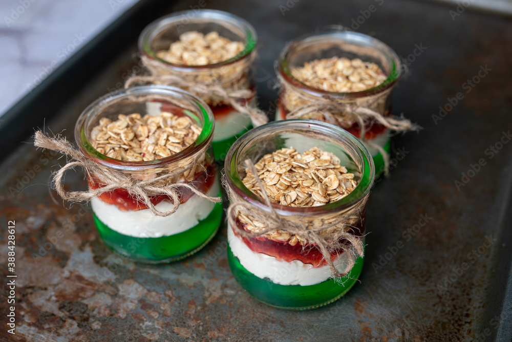 Yogurt with granola, decorated for Christmas with red and green jelly and jello. Christmas glass jar dessert