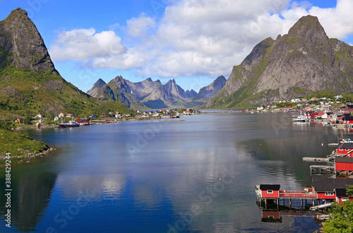 Sharp mountains, red huts and fishing boats reflected into the fjord in Reine, Lofoten Islands, Norway 