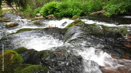 Wide high angle shot of downstream from Njupeskärs waterfall descending rocky steps between green forest in Fulufjällets National park, in Sweden photo