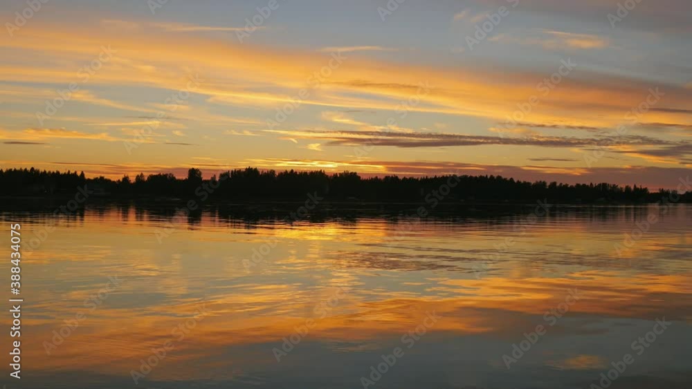 Lake view at sunset, afterglow in the sky and reflection of trees by the lake in the water, Jakobstad in Finland