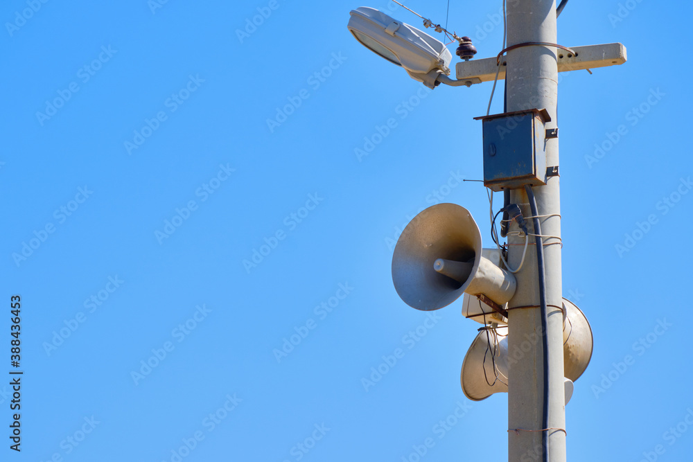 Speaker on the lighting pole. Means of warning in case of emergency. Against blue sky background copy space Speaker on the lighting pole. Means of warning in case of emergency. Against blue sky background copy space