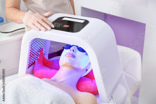 Woman undergoing procedure of facial chromotherapy in beauty salon