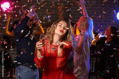 Young woman with glass of tasty champagne at party in nightclub