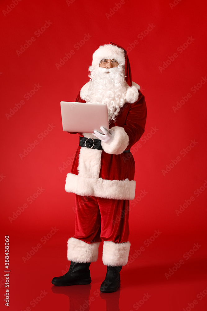 Santa Claus with laptop on color background Santa Claus with laptop on color background