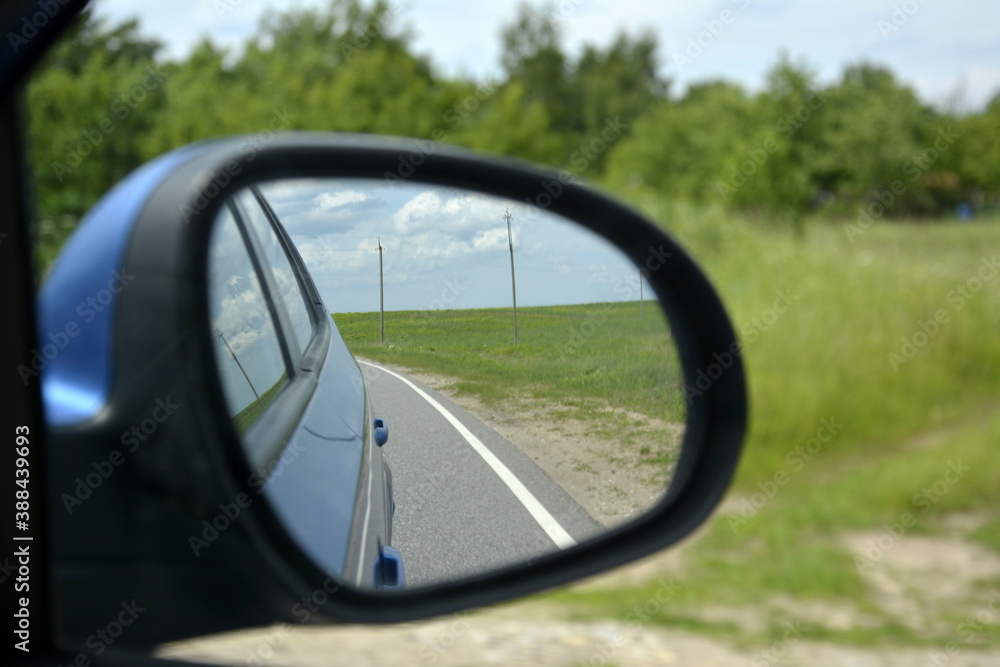 Saint Petersburg Russia. June 23 2016. Rural lanscape country road is reflected in side mirror of car during the summer trip perspective from automobile Saint Petersburg Russia. June 23 2016. Rural lanscape country road is reflected in side mirror of car during the summer trip perspective from automobile