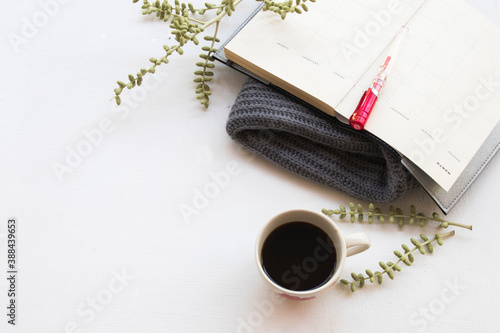notebook planner  for business work with hot coffee ,knitting wool scarf for winter season on table white at office desk