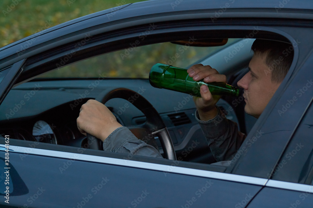 Man driving a car and drinking alcohol, drunk driving concept