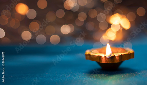 Diya lamps on a reflective base with glittering bokeh