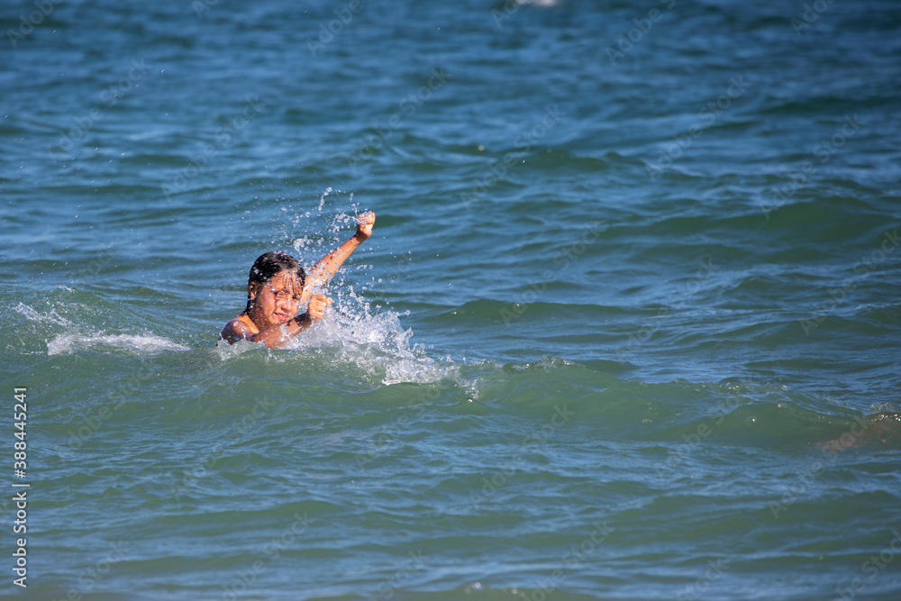 happy boy playing with waves in the sea, horizontal format
