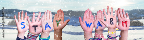 Children Hands Building Colorful English Word Stay Warm. Snowy Winter Background With Snowflakes