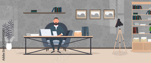 A businessman is working on a laptop in his office. Director's workplace. Laptop, documents, books, loft-style table. Vector.