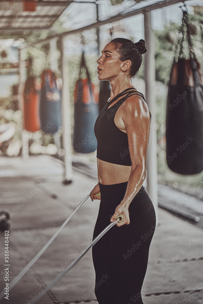 Attractive Young Fitness Woman Exercising Jumping Rope at gym