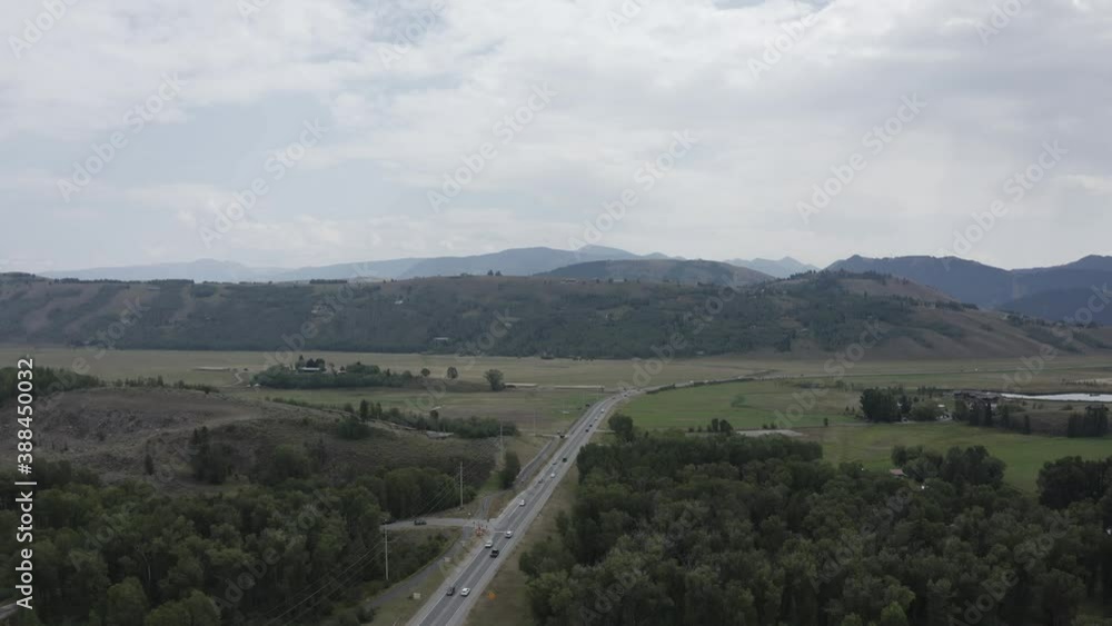 Aerial View of Highway Traffic Outside Jackson, Wyoming USA on Cloudy Summer Day looking Towards the Teton Mountain Range Green and Brown Landscape. Few Cars Due To Covid 19 Corona Virus Pandemic Aerial View of Highway Traffic Outside Jackson, Wyoming USA on Cloudy Summer Day looking Towards the Teton Mountain Range Green and Brown Landscape. Few Cars Due To Covid 19 Corona Virus Pandemic