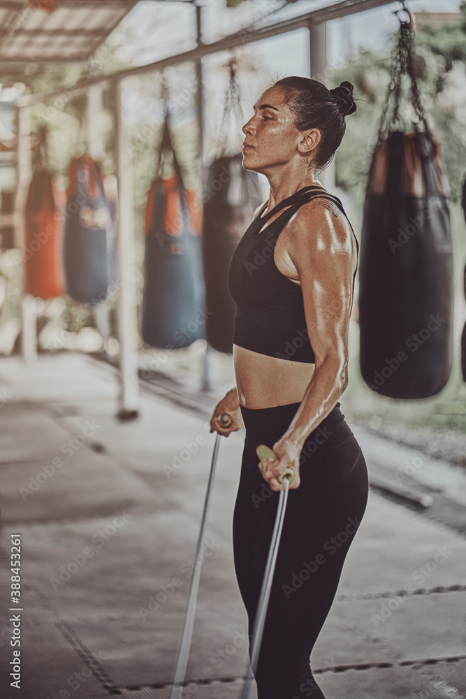 Attractive Young Fitness Woman Exercising Jumping Rope at gym
