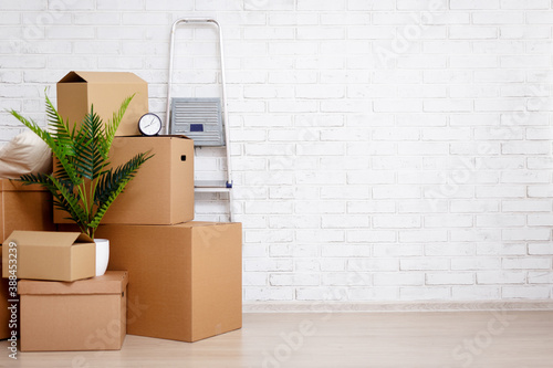 moving day concept - cardboard boxes, houseplants and other things over white brick wall background photo