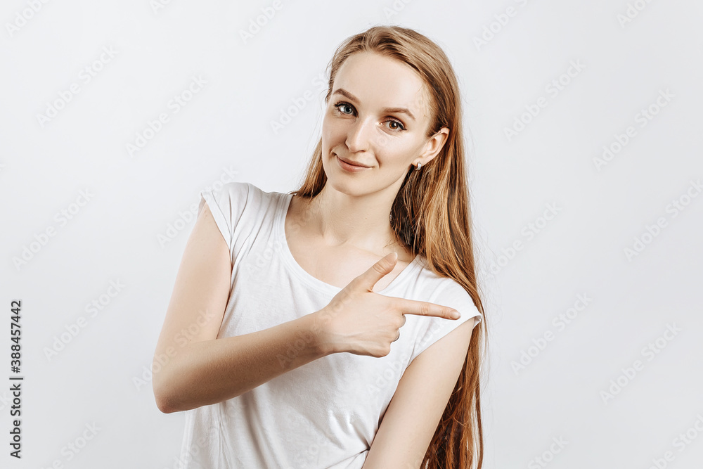 Young beautiful girl smiling and showing finger to the side on gray isolated background Young beautiful girl smiling and showing finger to the side on gray isolated background