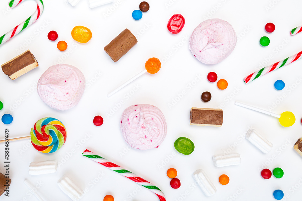 Many different sweets on a white background. Multicolored lollipops, caramel, candy canes, marshmallows, chocolate top view Many different sweets on a white background. Multicolored lollipops, caramel, candy canes, marshmallows, chocolate top view