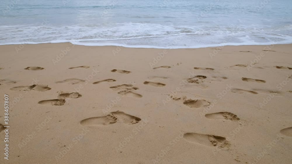 Footprints on the sandy beach. The sand and soft waves in the morning Footprints on the sandy beach. The sand and soft waves in the morning