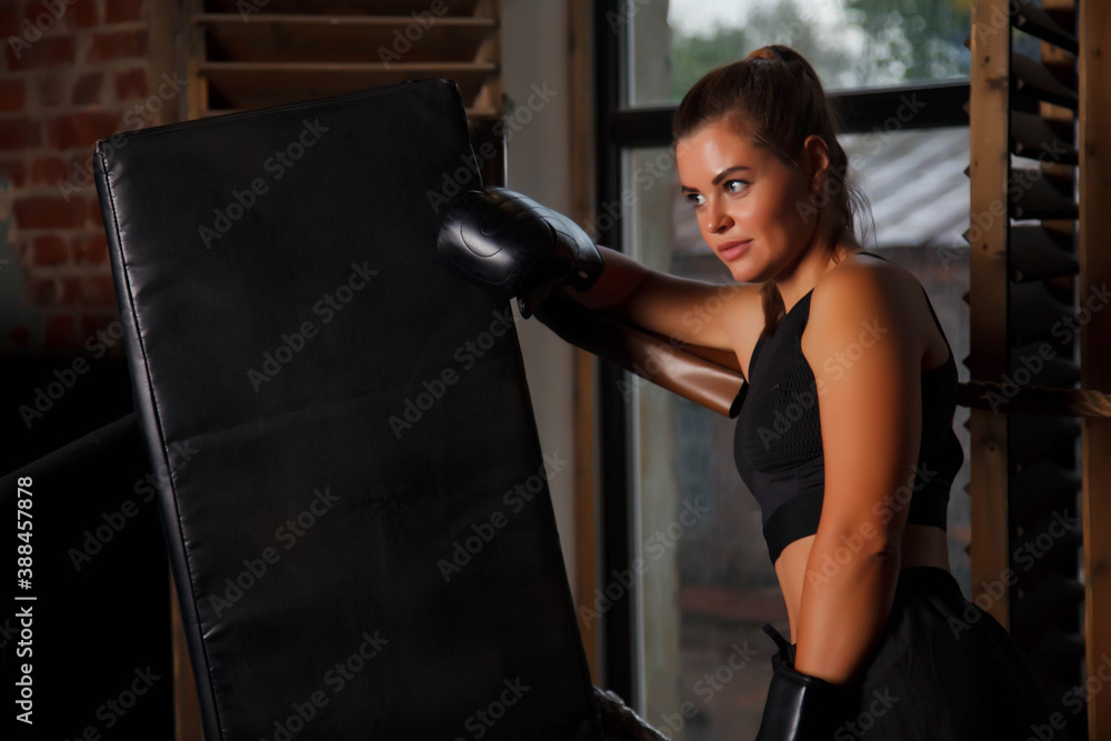 Pretty young female boxer stand in corner Boxing ring holding up hands in an old gym, her hand in gloves. Woman in box training. Concept of healthy lifestyle, sports and exercise in gym. Copy space
