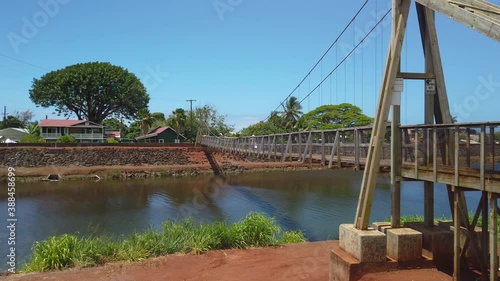 4K slight left to right panning motion of woman crossing the Hanapepe swinging bridge, Wooden bridge built in early 1900,Kauai,Hawaii,USA photo