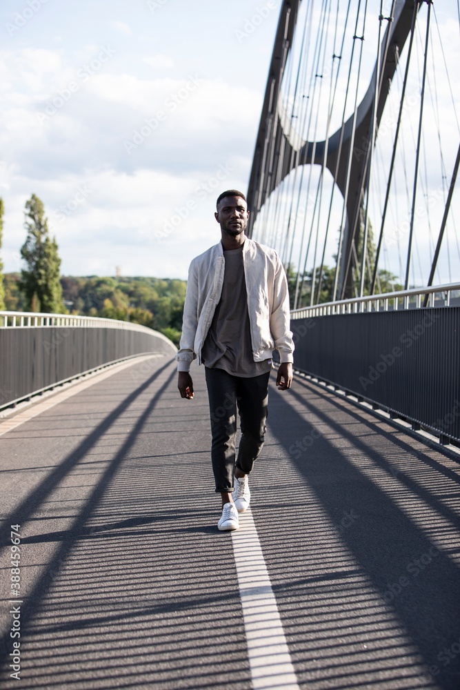 Young Black Man Walking Confidently on Bridge