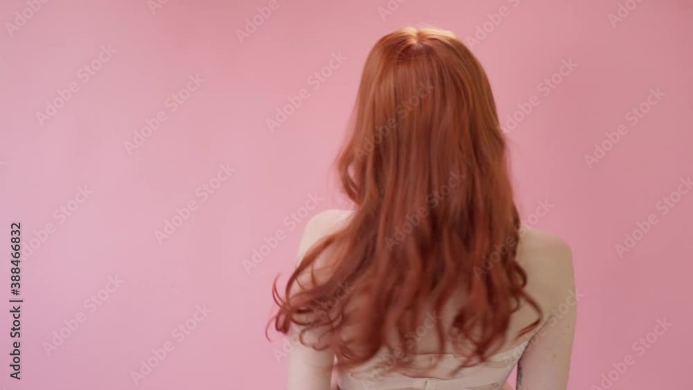 Beautiful fashionable girl with long curly red hair. Girl in the studio on a pink background. Advertising, hair products, beauty salon, cosmetics, clothing. Fashion, boutique. Pink. Beautiful fashionable girl with long curly red hair. Girl in the studio on a pink background. Advertising, hair products, beauty salon, cosmetics, clothing. Fashion, boutique. Pink.