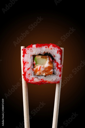 roll with salmon on chopstick on black background