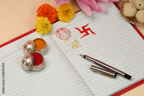 Red accounting note book / bahi khata with goddess Laxmi idol coin, diya, sweets, lotus, pen with ink on Laxmi pujan, Diwali Festival photo