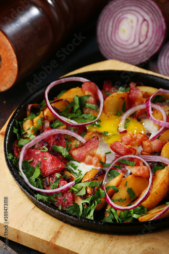 frying pan with potatoes meat and vegetables closeup with ingredients on background
