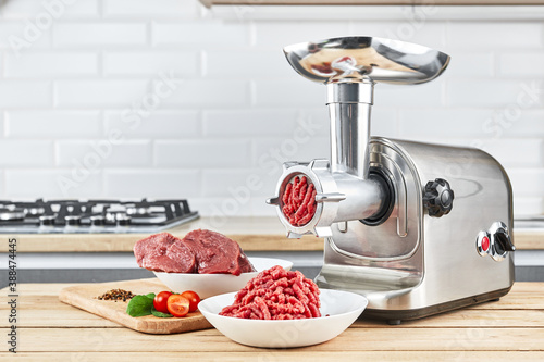 Foto Bowl of mince with electric meat grinder in kitchen interior