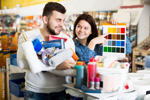 Smiling couple examining color scheme variants in paint supplies supermarket