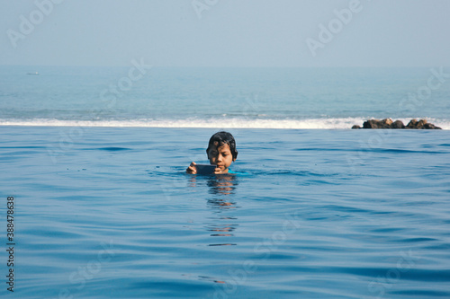 Joyful Asian boy using smartphone in the swimming pool. Technology, summer and holiday concept © Gatot