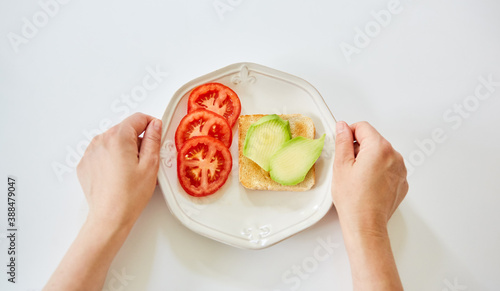 Hände vor Toast mit Avocado und Tomate
