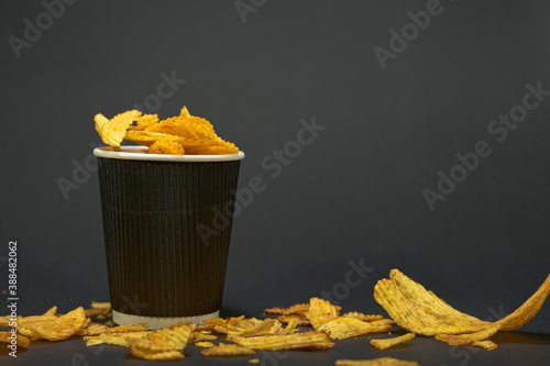 pread potato chips and chips in a cup on black background photo