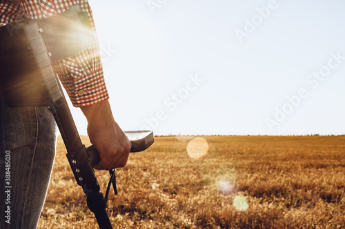 Man with metal detector equipment searching for metal goods in the field