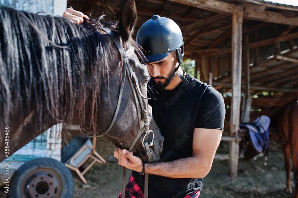 Arab tall beard man wear in black helmet with arabian horse. Arab tall beard man wear in black helmet with arabian horse.