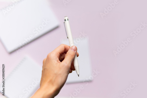 business composition with notebooks and pens on a pink background with a place to write. Business concept with hands holding a pen