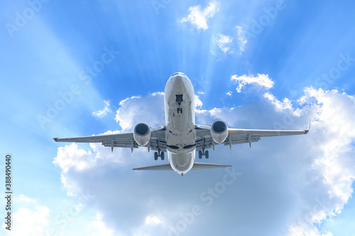 Commercial airplane flying above blue sky and white clouds.